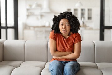 Fototapeta premium Mental Breakdown. Concerned Young Black Woman Sitting On Couch At Home