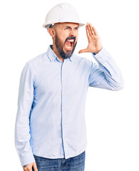 Young handsome man wearing architect hardhat shouting and screaming loud to side with hand on mouth. communication concept.