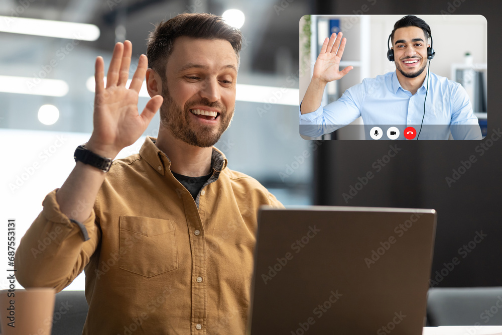 Poster man waving hello to laptop making video call in office