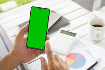 Businessmen use an empty smartphone at the coffee shop. His Hands are touching the green phone screen. For the creators to put in additional images. Financial development, Banking Account, Statistics