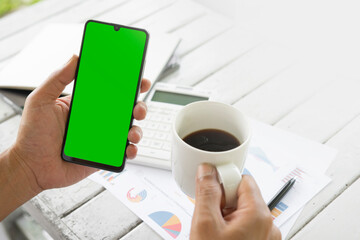 Businessmen use an empty smartphone at the coffee shop. His Hands are holding the smartphone with a green screen. For the creators to put in additional images. Financial development, Banking Account, 