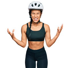 Beautiful hispanic woman wearing bike helmet crazy and mad shouting and yelling with aggressive expression and arms raised. frustration concept.