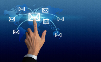 Communication concept: Businessman hand pressing a letter or email icon on a world map interface,...