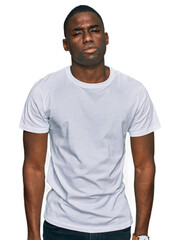 Young african american man wearing casual white t shirt looking sleepy and tired, exhausted for...