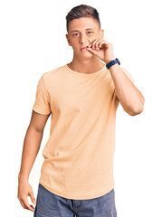 Young handsome man wearing casual clothes mouth and lips shut as zip with fingers. secret and...
