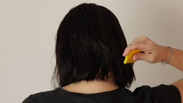 femme passant un peigne &agrave; poux dans ses cheveux