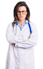 Fototapeta premium Young beautiful woman wearing doctor stethoscope and glasses skeptic and nervous, disapproving expression on face with crossed arms. negative person.
