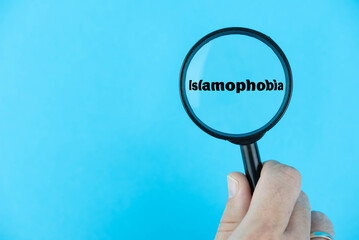 Global surge in Islamophobia, portrayed through a magnifying glass focused on the word “Islamophobia”. A poignant reflection on the alarming spread of bias and discrimination worldwide - obrazy, fototapety, plakaty