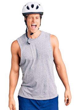 Young handsome man wearing bike helmet winking looking at the camera with sexy expression, cheerful and happy face.