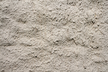 Abstract textured light beige wall background. Close-up view of old weathered cement wall with material drips in a sunny day. Copy space for your text. Architecture backdrops theme.