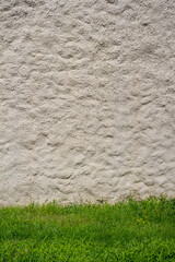 Abstract textured wall background. Close-up view of old weathered cement building wall with material drips standing by green grass. Copy space for your text. Architecture backdrops theme.