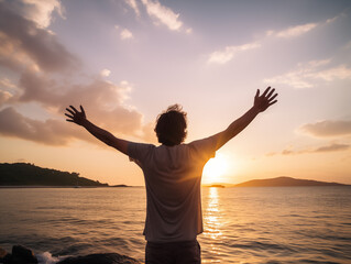 Fototapeta premium Embrace the Golden Hour: A solitary figure stands on a rocky beach, arms outstretched towards a breathtaking sunset, symbolizing freedom, tranquility, and the beauty of nature's embrace. 