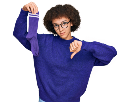 Young hispanic girl holding sporty sock with angry face, negative sign showing dislike with thumbs down, rejection concept