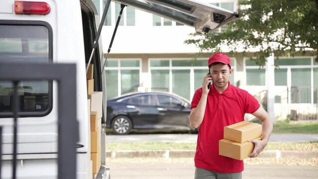 Handsome Asian man holding a cardboard parcel box standing in front of a house with a van in the background, delivery concept. 4K resolution.