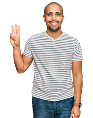 Naklejka premium Hispanic adult man wearing casual clothes showing and pointing up with fingers number three while smiling confident and happy.