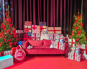 Decorated xmas with Merry Christmas gifts in cozy Santa home interior, banner. Happy New Year presents boxes in workshop late in night with lights on xmas tree, holiday eve background