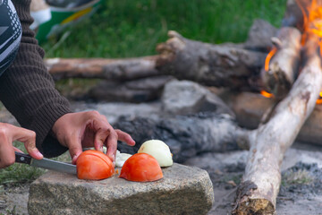 cocinando verduras en un sarten cerca de la fogata para campamento de verano - obrazy, fototapety, plakaty
