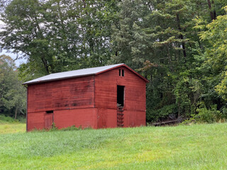 Obraz premium Red barn on grassy green hill