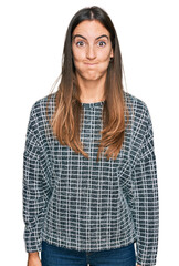Young beautiful woman wearing casual clothes puffing cheeks with funny face. mouth inflated with air, crazy expression. - obrazy, fototapety, plakaty