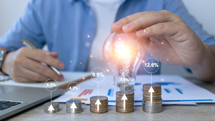 Interest rate and dividend concept.Businessman touch light bulb to idea stacking coins and...