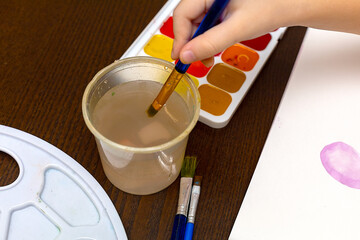 Child draws the home watercolors. the child draws with paints