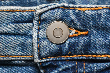 Metal button trousers. Blue jeans denim fabric. Grunge fashion background pattern with closeup on...