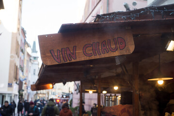 Mulhouse - France - 3 December 2023 - Closeup of mulled wine sign on wooden cabin at the christmas market with text in french : vin chaud, traduction in english of mulled wine - 687583773