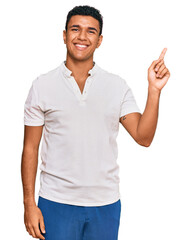 Young arab man wearing casual clothes with a big smile on face, pointing with hand finger to the side looking at the camera.