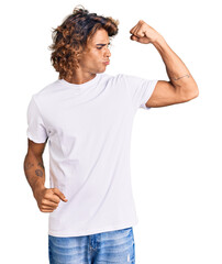 Young hispanic man wearing casual white tshirt showing arms muscles smiling proud. fitness concept.