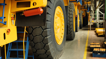 Assembly line of large dump trucks. Finished dump trucks are lined up in a production shop. A...