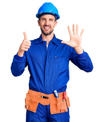 Young handsome man wearing worker uniform and hardhat showing and pointing up with fingers number six while smiling confident and happy.