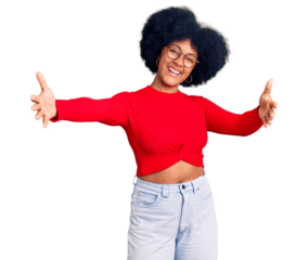 Young african american girl wearing casual clothes and glasses looking at the camera smiling with open arms for hug. cheerful expression embracing happiness.