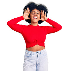 Fototapeta na wymiar Young african american girl wearing casual clothes and glasses smiling cheerful playing peek a boo with hands showing face. surprised and exited