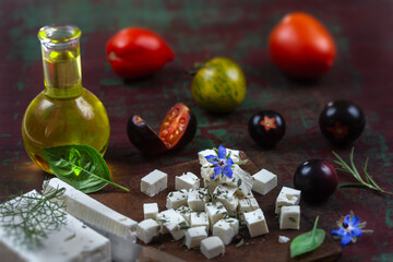 Bottle of olive oil and tomatoes with leaves feta cheese and basil isolated on a brown background