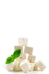 Cube Feta cheese isolated on white background clipping Heap of Feta cheese, basil leaves and tomatoes.