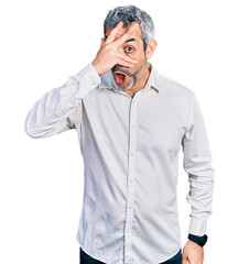 Middle age hispanic with grey hair wearing casual white shirt peeking in shock covering face and eyes with hand, looking through fingers with embarrassed expression.