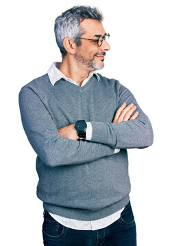 Middle age hispanic with grey hair wearing glasses looking to the side with arms crossed convinced and confident