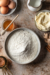 Baking ingredients and kitchen utensils on brown background top view. Flour, eggs, milk, honey, butter, spices on kitchen table. Flat lay
