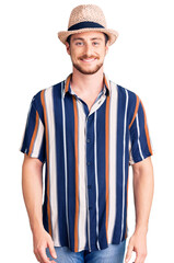 Young handsome caucasian man wearing summer hat with a happy and cool smile on face. lucky person.