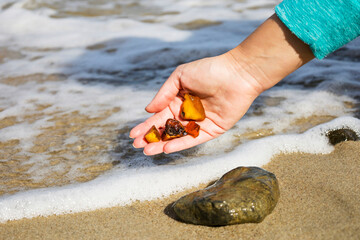 Beautiful pieces of amber in the hand of the sea background. A glowing wavy piece of amber in the...