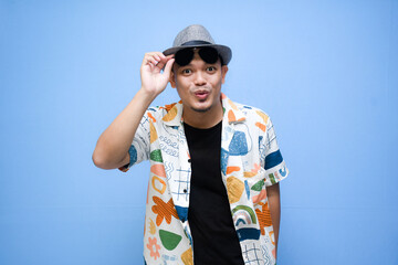 Smiling asian man wearing beach shirt and glases isolated on blue background. Vacation concept
