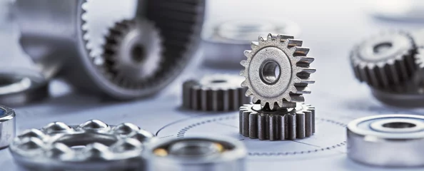 Fotobehang Close up metal gears and bearings. Background with drawings of the mechanism. Industrial mechanism. © evkaz