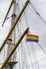 Historic ship mast and rigging with a rainbow pride flag flying