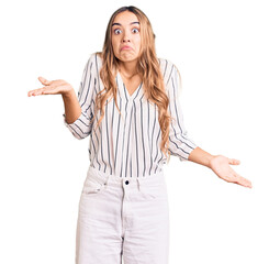 Young beautiful blonde woman wearing casual clothes clueless and confused expression with arms and...