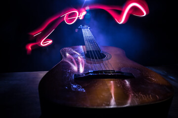 Music concept. Acoustic guitar isolated on a dark background under beam of light with smoke with...