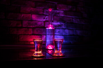 Cold vodka glass on a dark background in the neon light or glasses of russian vodka on bar...