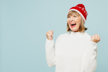 Side view merry elderly woman 50s years old wear sweater red hat posing do winner gesture celebrate...