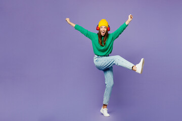 Full body young woman wear green sweater yellow hat casual clothes listen to music in headphones...