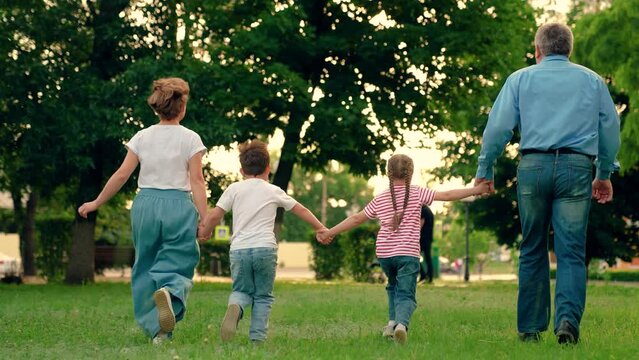 Happy family team, children, parents, run together in park on grass. Weekend play, holiday kids. Children, mom dad playing, kids in nature. Family game Concept, father mother daughter son fun running