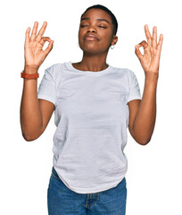 Young african american woman wearing casual white t shirt relaxed and smiling with eyes closed doing meditation gesture with fingers. yoga concept.